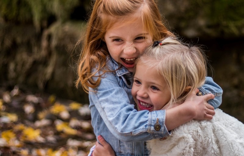 To smilende små jenter omringet av høstblader