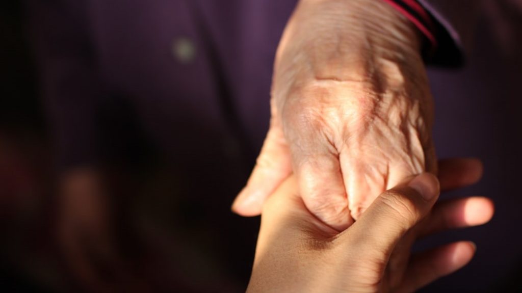 en eldre og en yngre person som holder hender